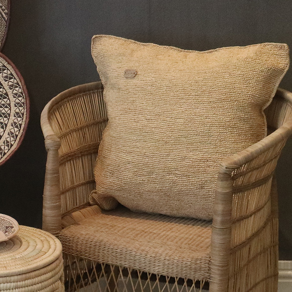 Woven chair with beige cushion and decorative baskets in a cozy setting.