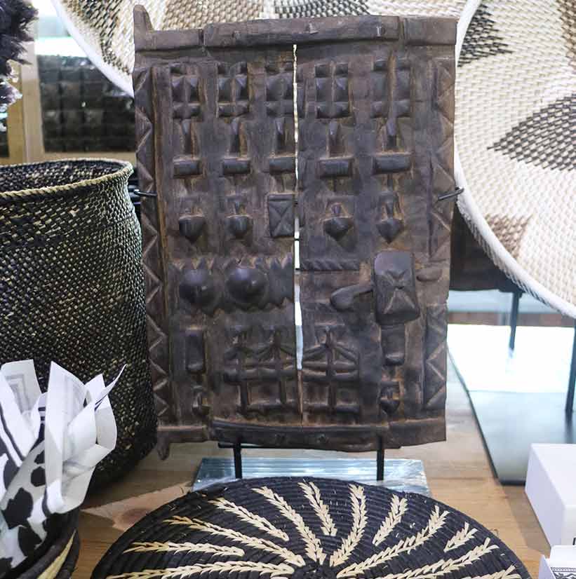 African carved wooden panel displayed with woven baskets.